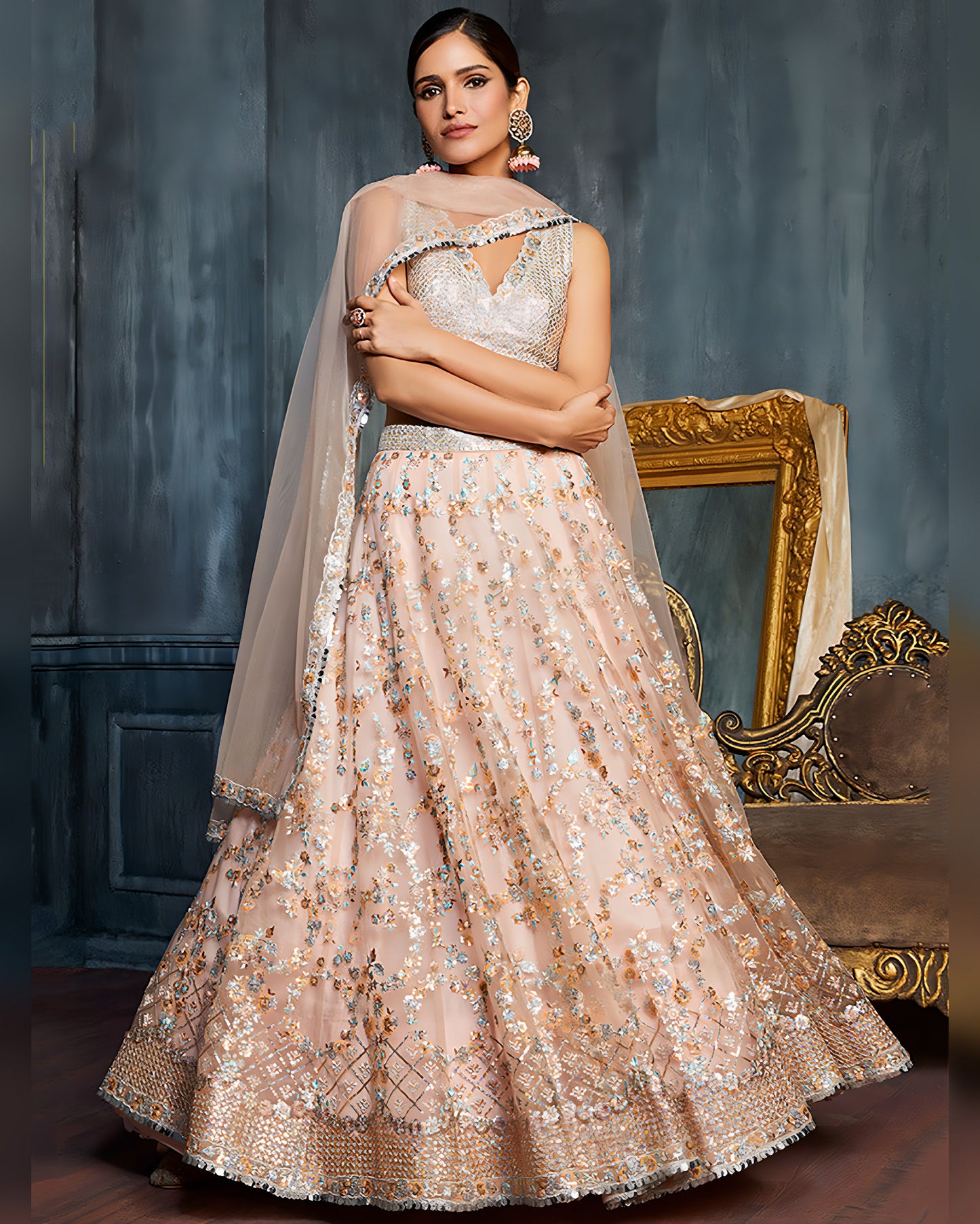 Woman in a beige embroidered lehenga with a gold frame in the background