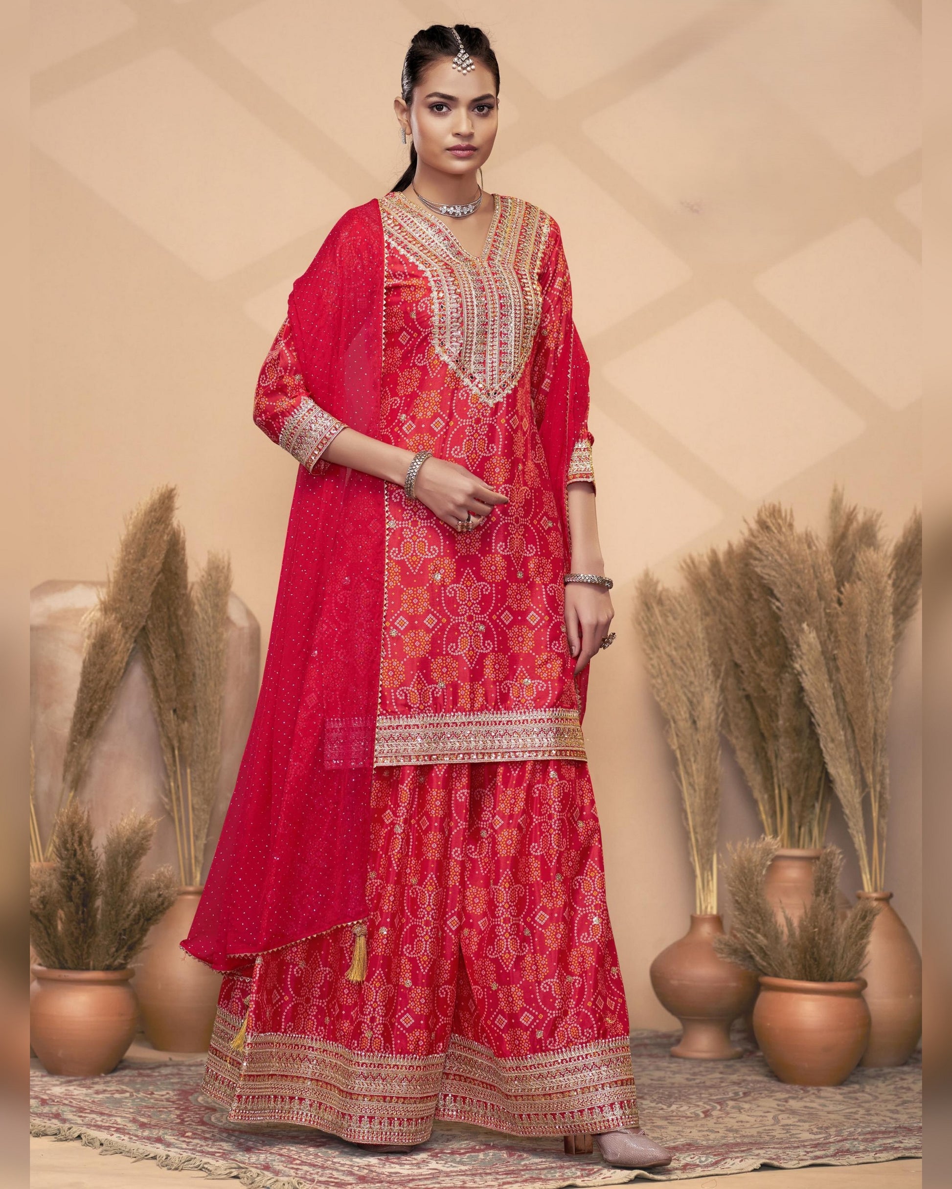 Woman wearing a red traditional outfit with intricate patterns in a decorative setting.