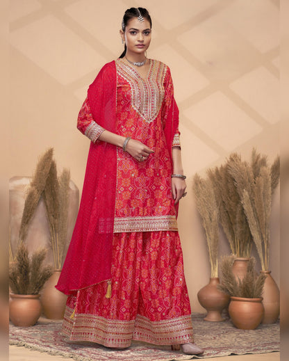 Woman wearing a red traditional outfit with intricate patterns in a decorative setting.