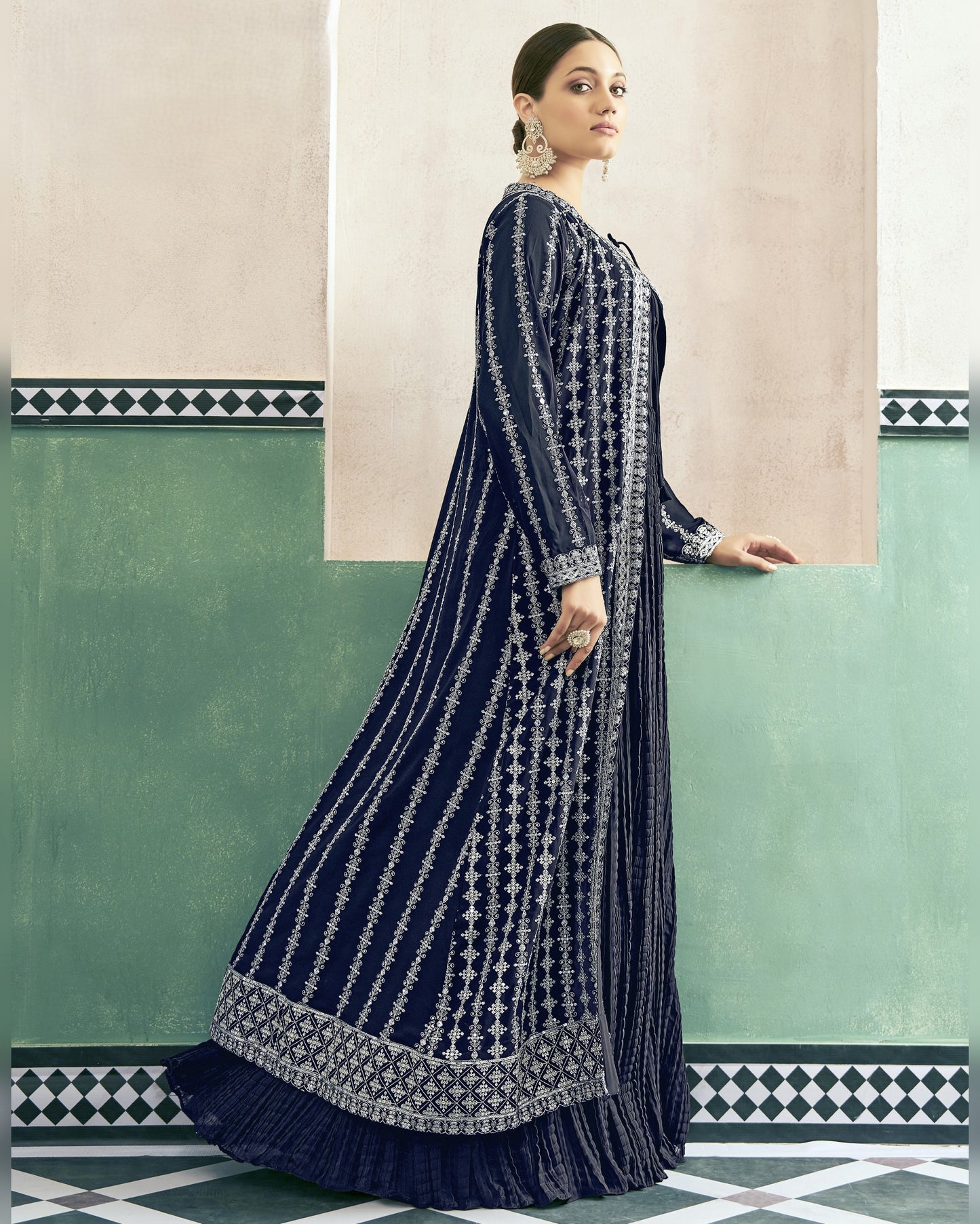Woman wearing a navy blue and white patterned dress against a green and beige wall.