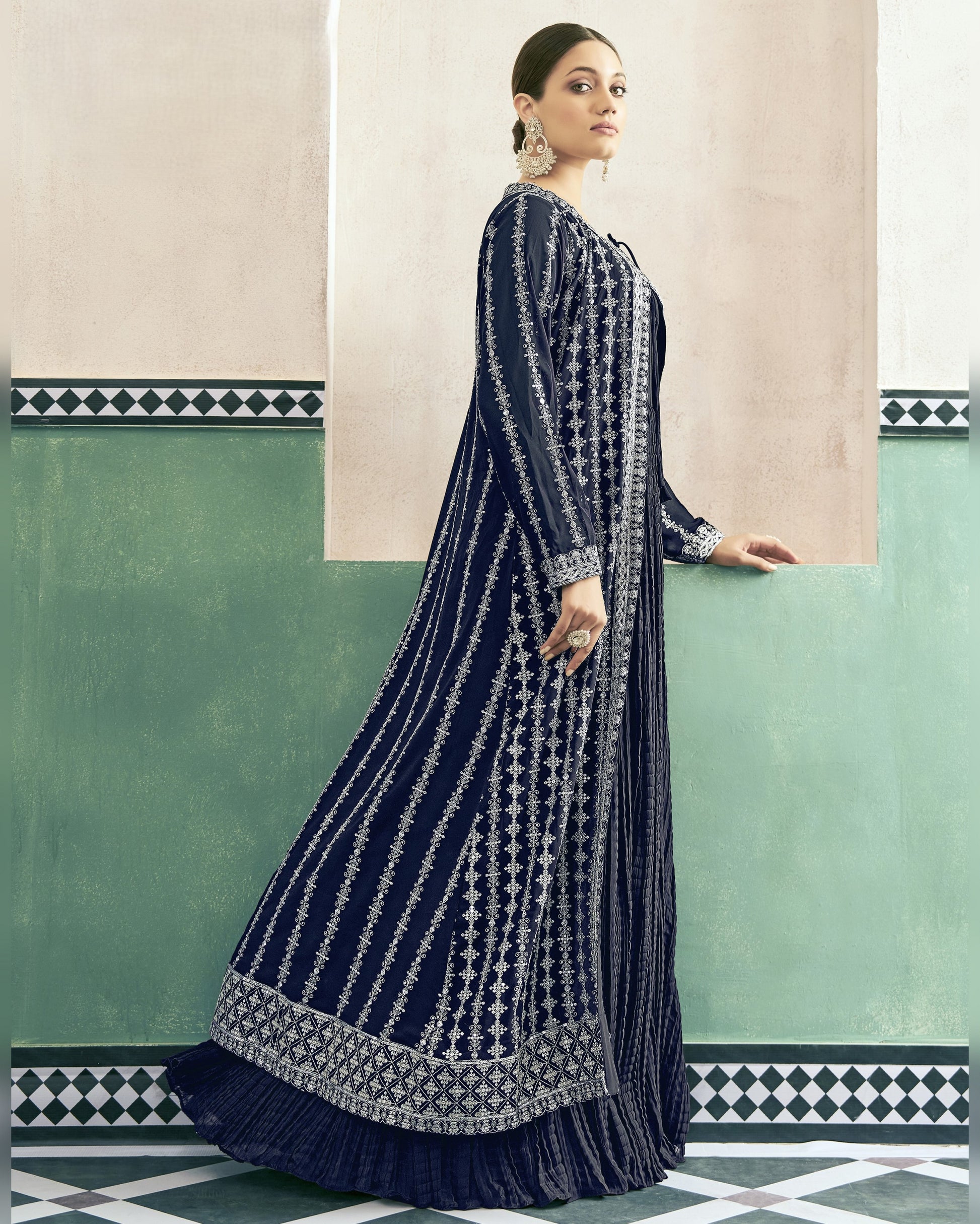 Woman wearing a navy blue and white patterned dress against a green and beige wall.