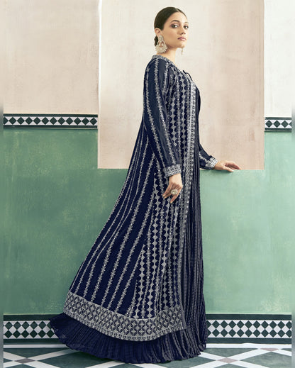 Woman wearing a navy blue and white patterned dress against a green and beige wall.