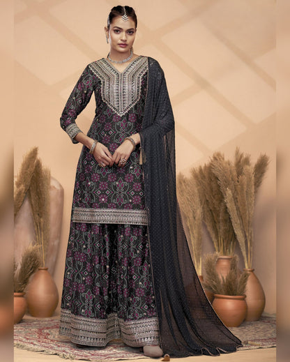 Woman wearing a traditional outfit with intricate patterns in a decorative setting.