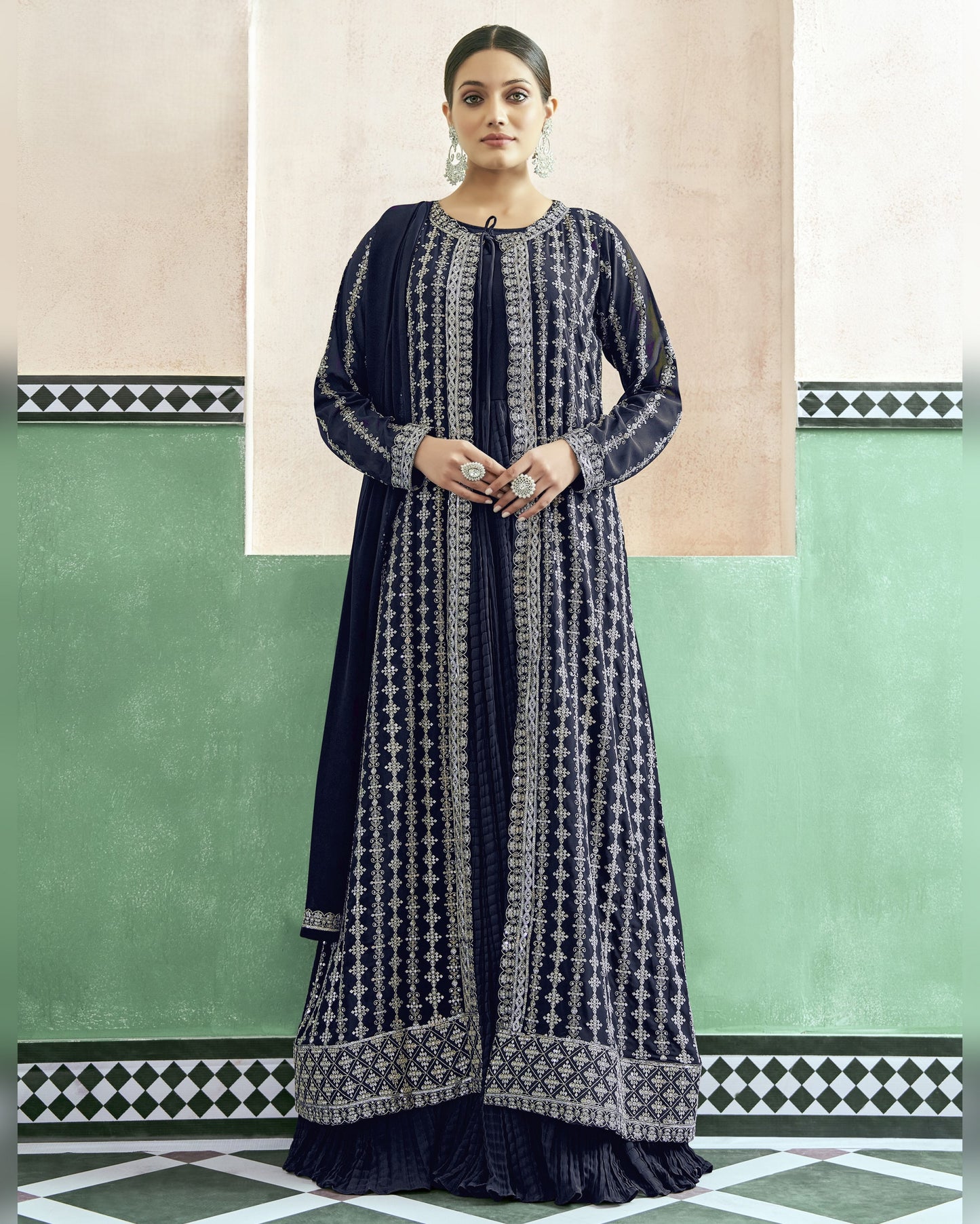 Woman wearing a navy blue and white patterned dress against a green and beige wall.