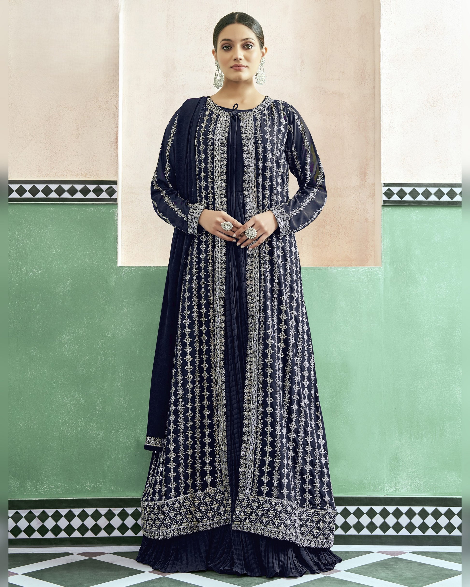 Woman wearing a navy blue and white patterned dress against a green and beige wall.