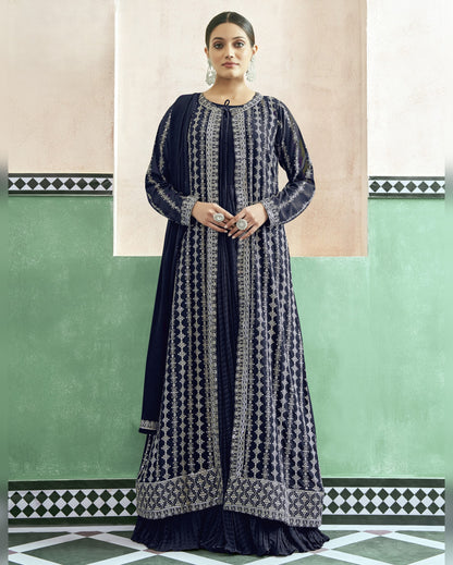Woman wearing a navy blue and white patterned dress against a green and beige wall.