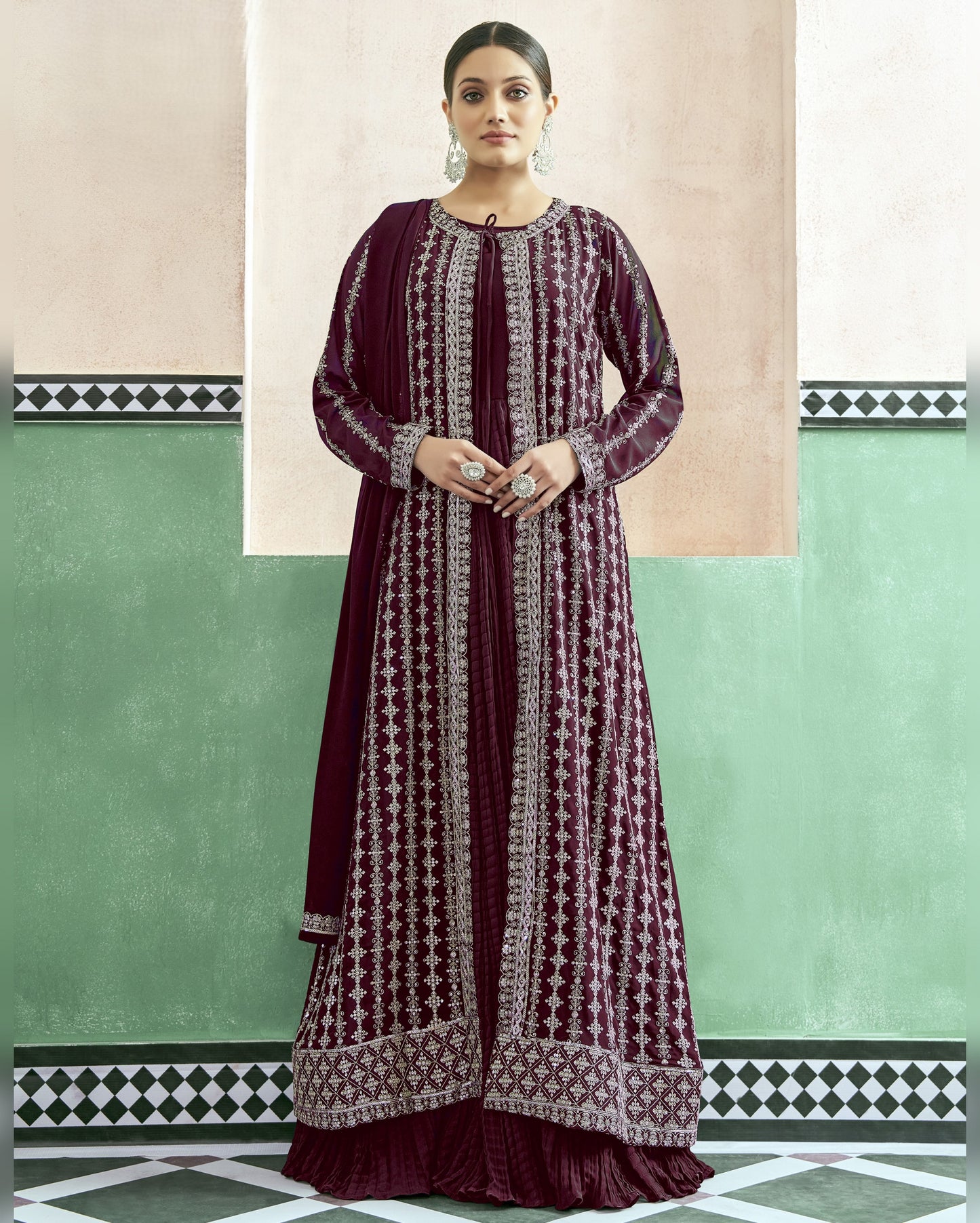 Woman wearing a long, patterned dress against a green and beige wall.