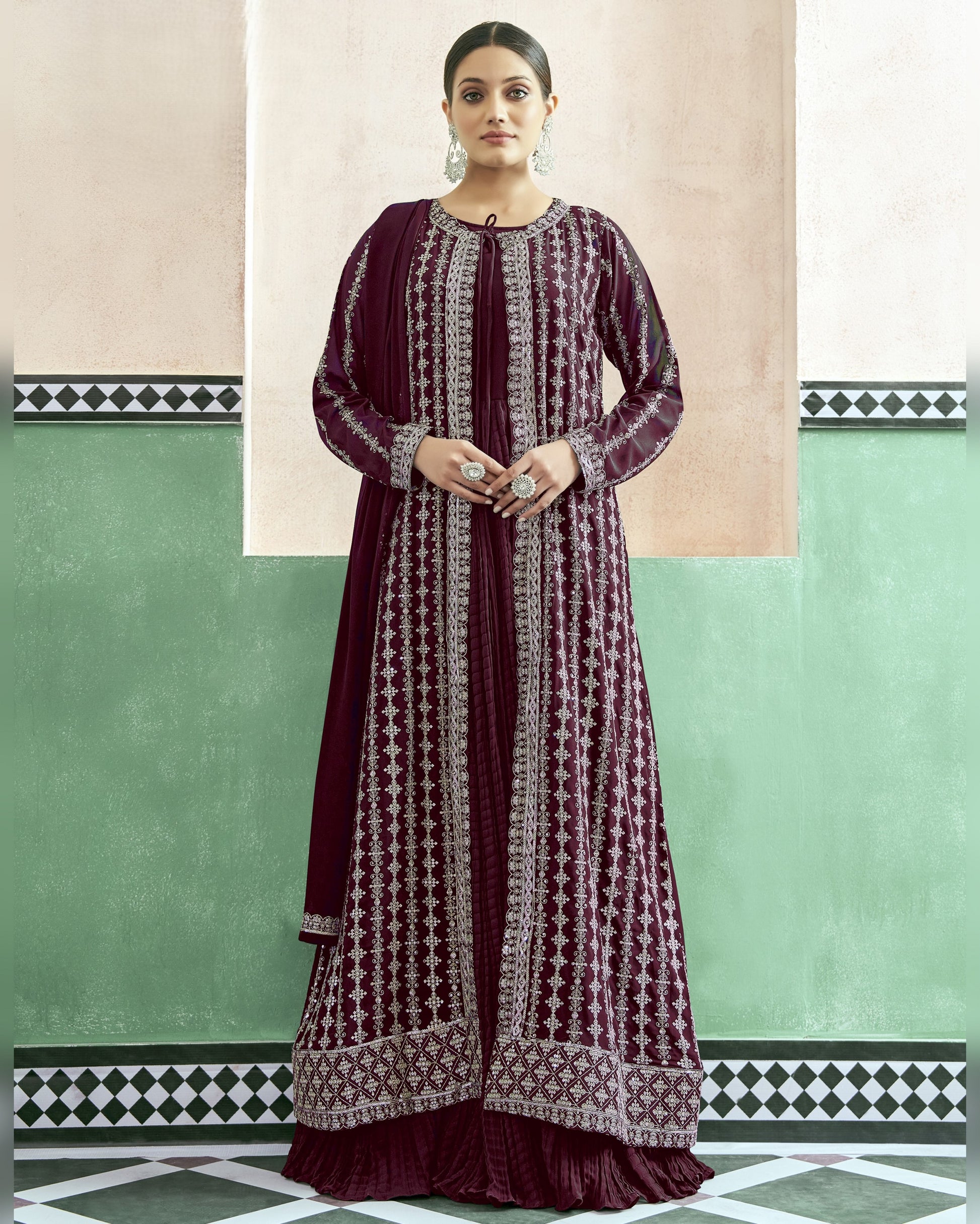 Woman wearing a long, patterned dress against a green and beige wall.