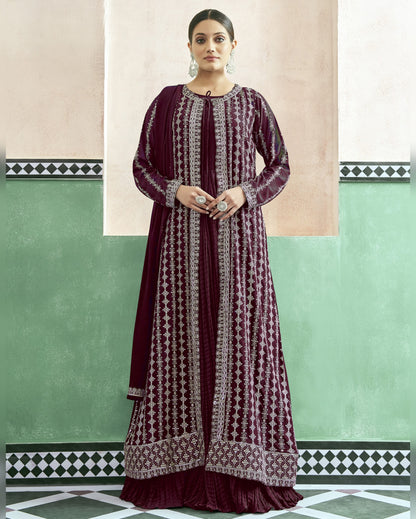 Woman wearing a long, patterned dress against a green and beige wall.