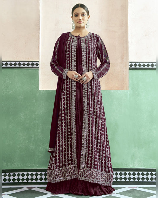 Woman wearing a long, patterned dress against a green and beige wall.