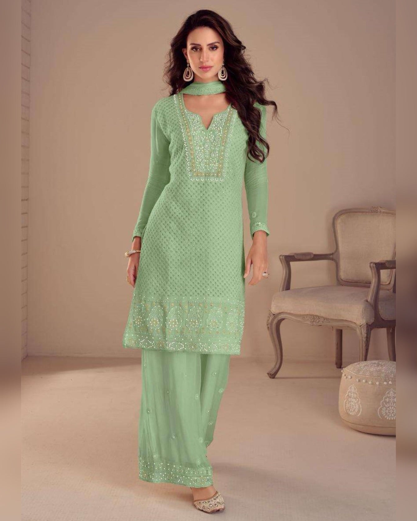 Woman wearing a light green traditional outfit with embroidery in a neutral setting