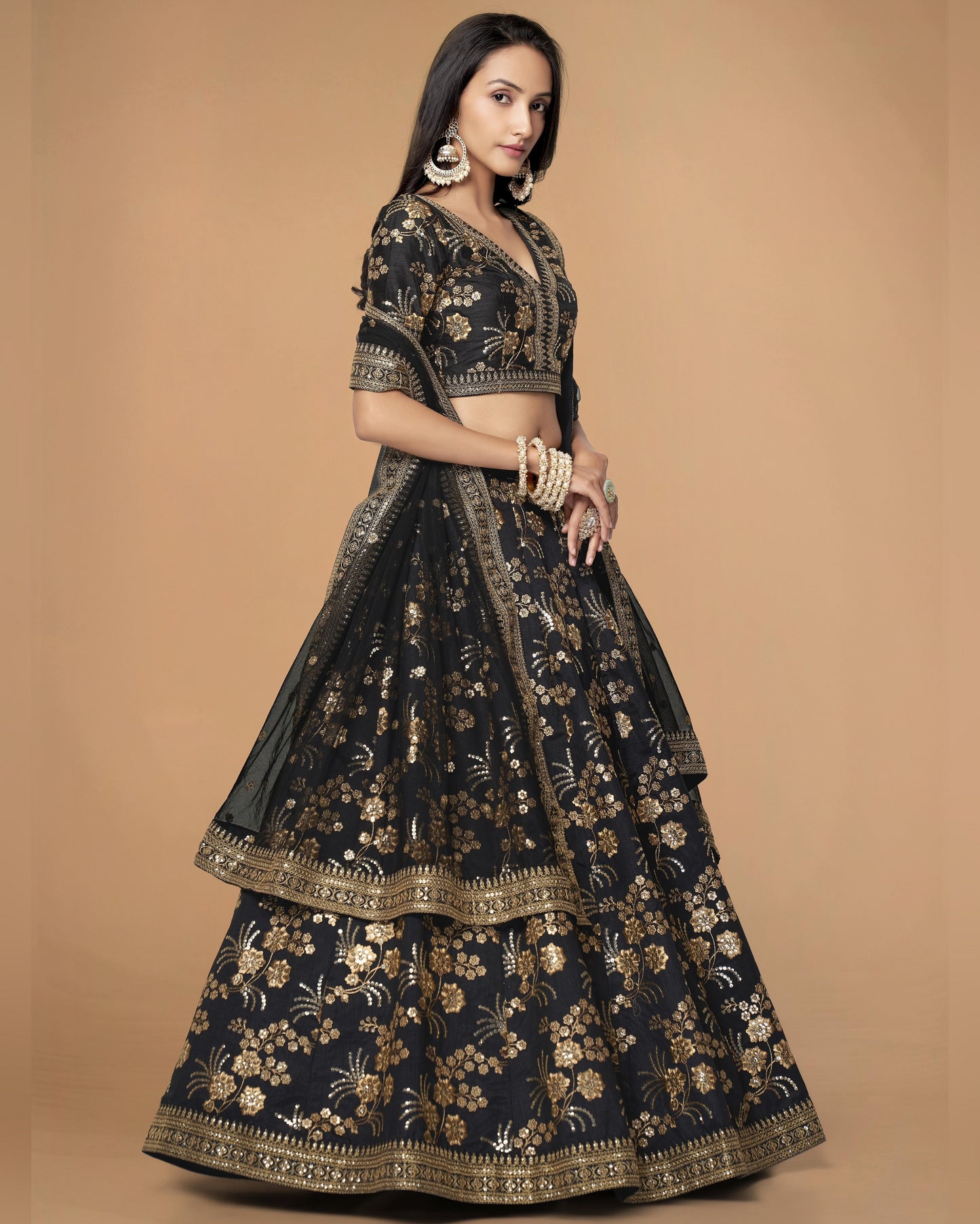 Woman wearing a black and gold embroidered traditional outfit on a beige background