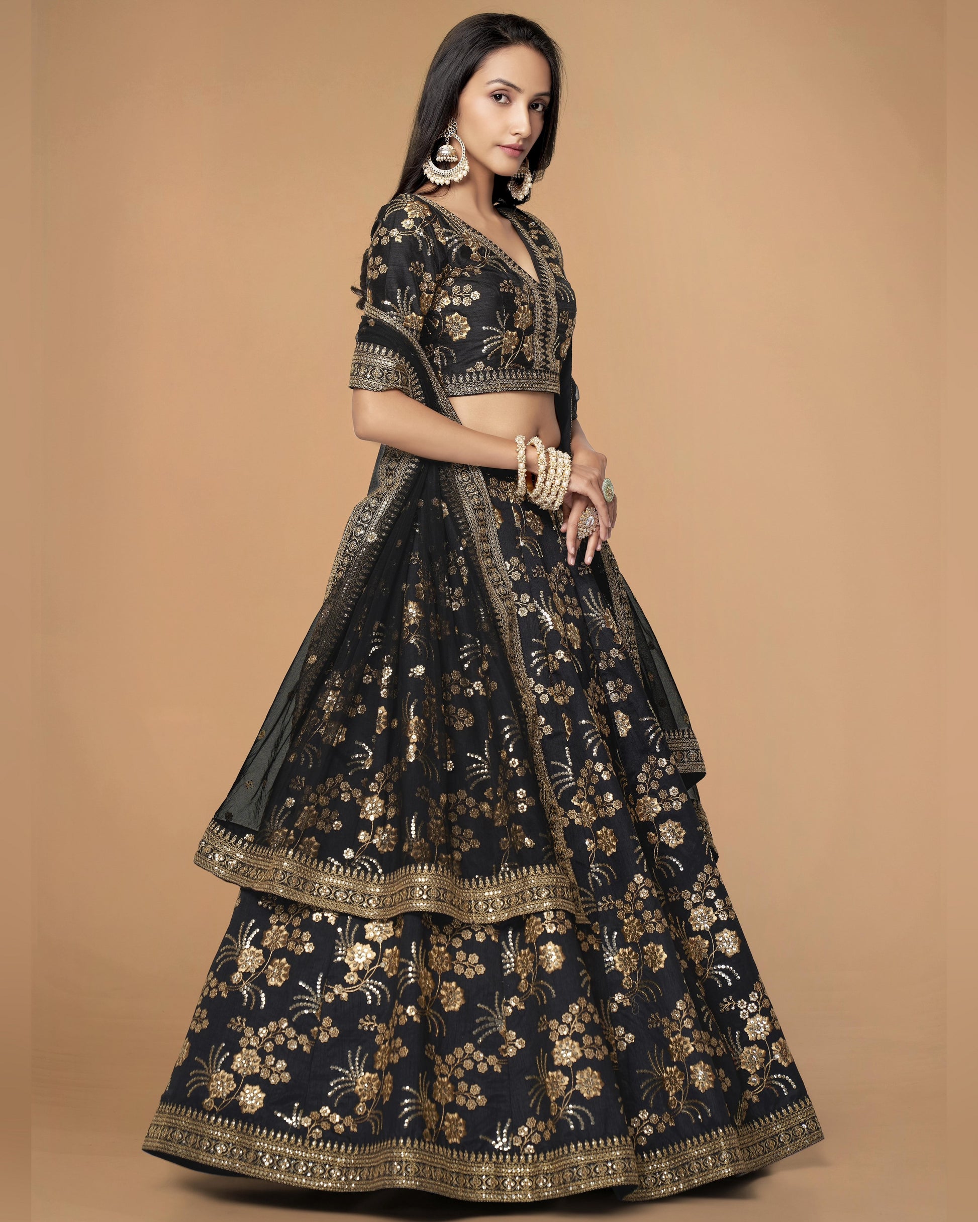 Woman wearing a black and gold embroidered traditional outfit on a beige background