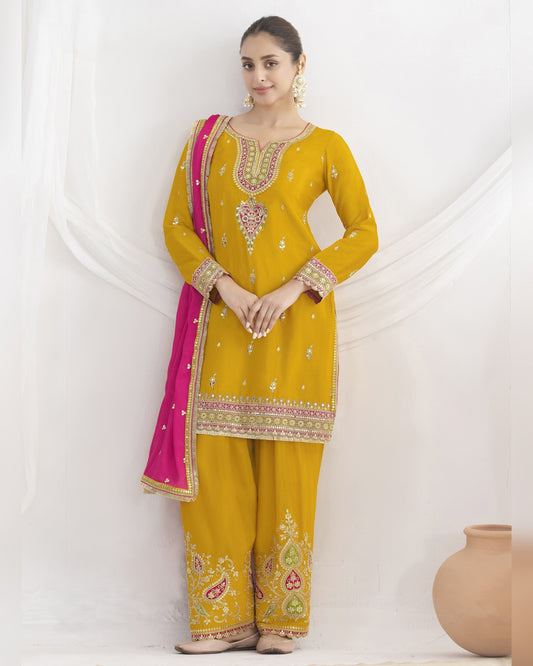 Woman wearing a yellow embroidered traditional outfit with a pink dupatta on a white background