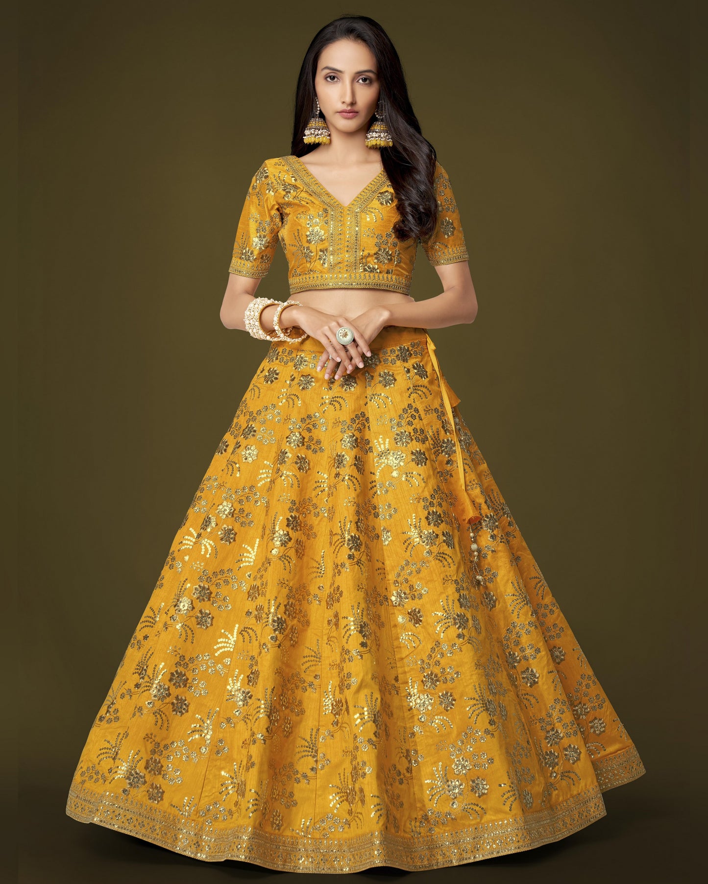 Woman wearing a yellow embroidered traditional outfit on a dark background