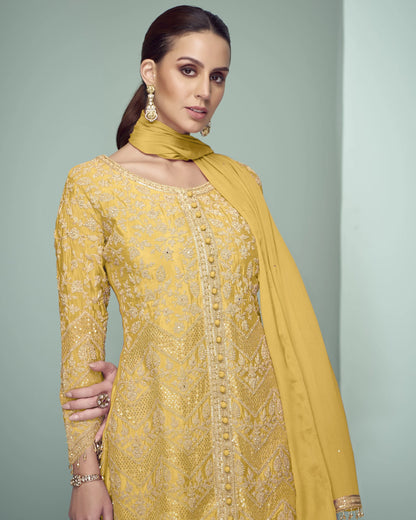 Woman wearing a yellow embroidered outfit with a matching dupatta against a gray background